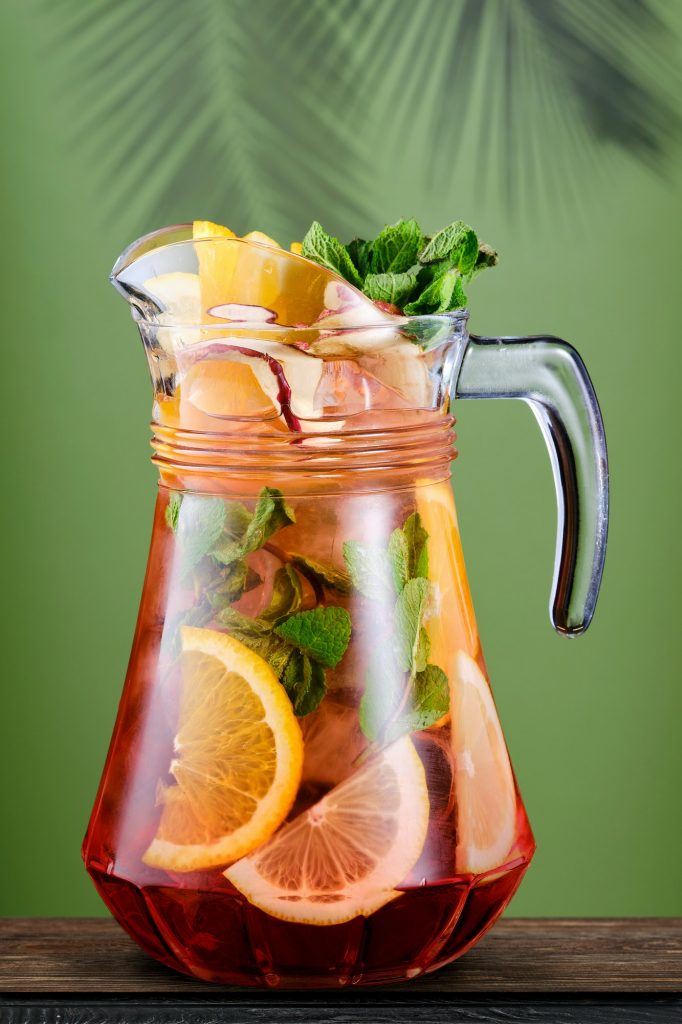 Pitcher with cold sangria over green background